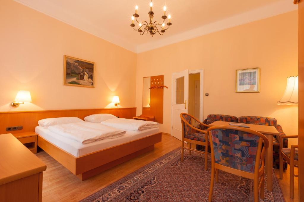 a bedroom with a bed and a table and chairs at Pension Elfy in Baden