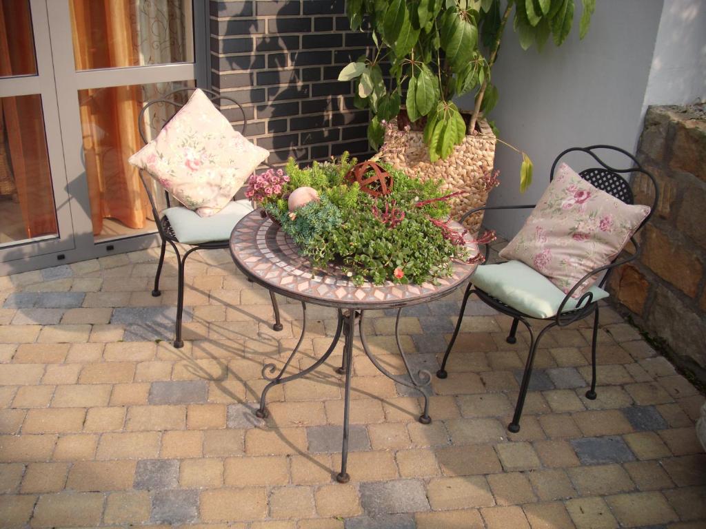 a patio with two chairs and a table with a plant at Villa Fleurie in Schledehausen