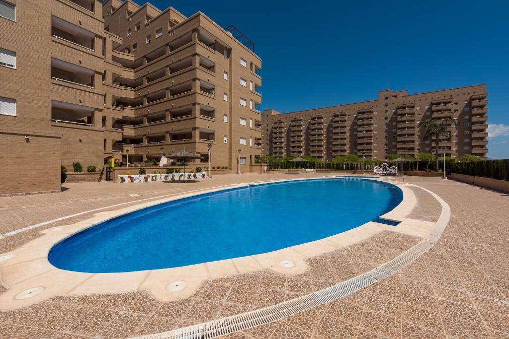 オロペサ・デル・マールにあるApartamentos Jardines del Mar IIの一部の建物の前に大きなスイミングプールがあります。