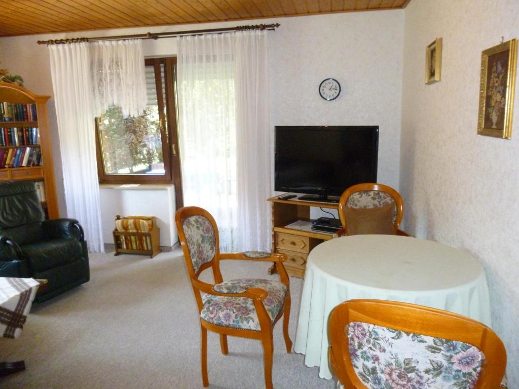ein Wohnzimmer mit einem Tisch, Stühlen und einem TV in der Unterkunft Anton Schuler in Niedenstein