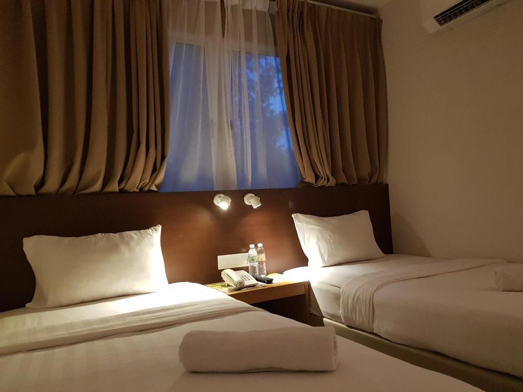 a hotel room with two beds and a window at Hotel Asia in Kuah