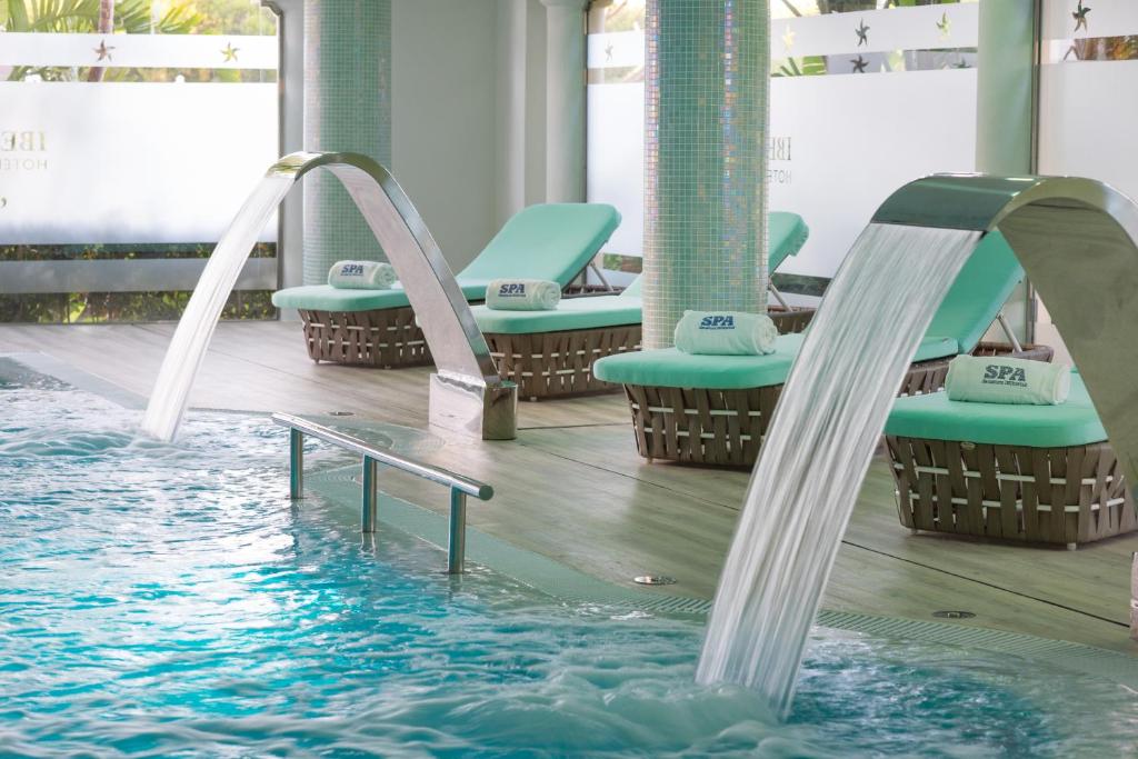 a pool with chairs and a slide in the water at Iberostar Selection Andalucia Playa in Chiclana de la Frontera