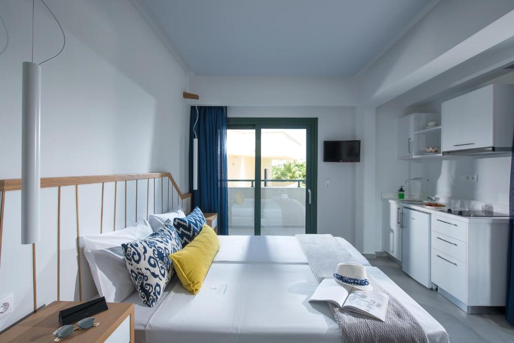 a bedroom with a large white bed and a kitchen at Kristalli Hotel Apartments in Malia