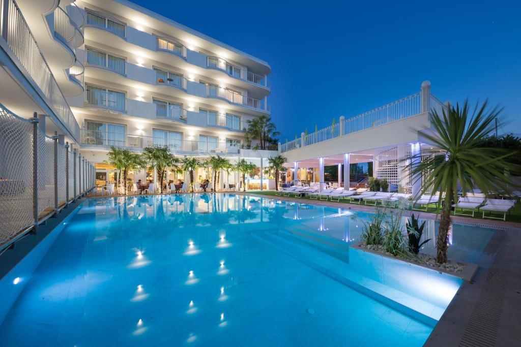 a swimming pool in front of a hotel at night at AQA Palace in Caorle