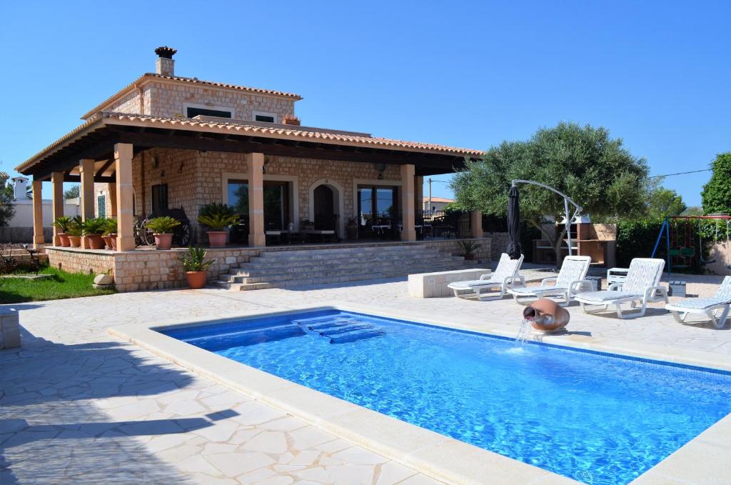 a villa with a swimming pool in front of a house at Ca Na Marina in Cala Llombards