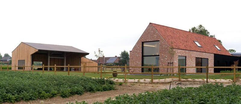 ein großes Backsteinhaus mit einer Scheune auf einem Feld in der Unterkunft gastenverblijf 't Baertshof in Zonnebeke