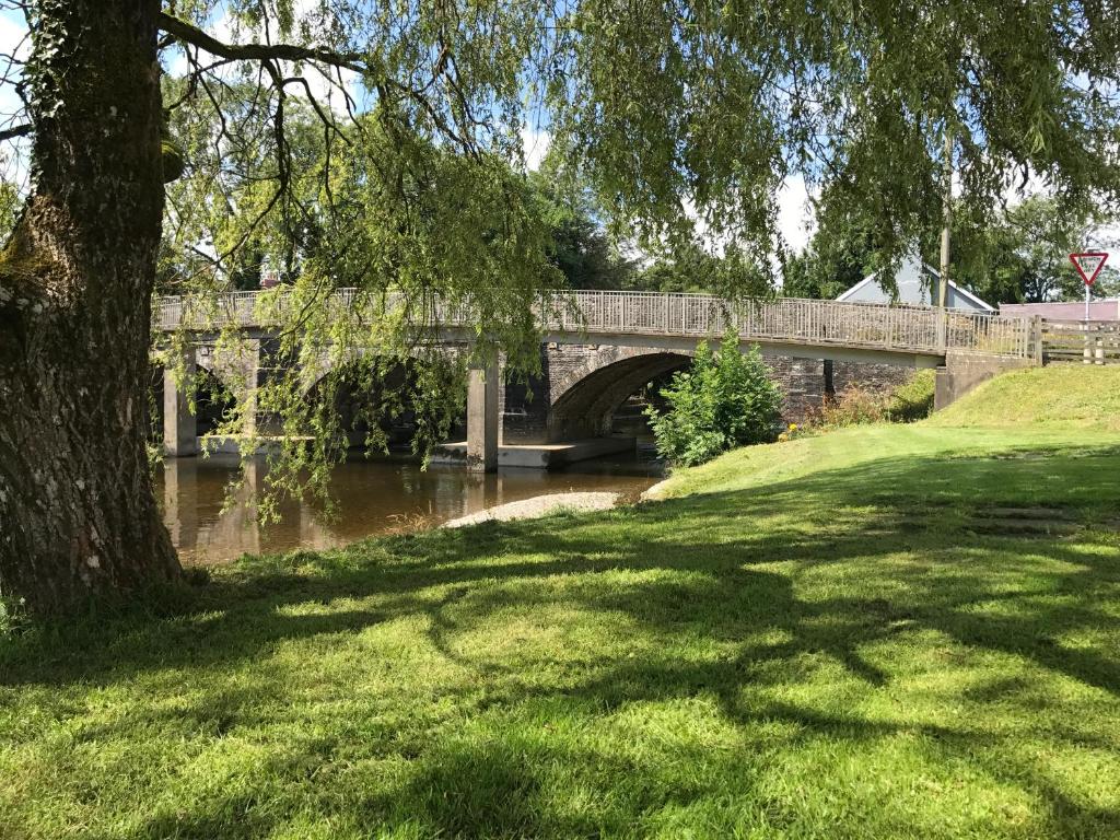 a stone bridge over a river with a grass field at The Cothi Bridge Apartments in Carmarthen