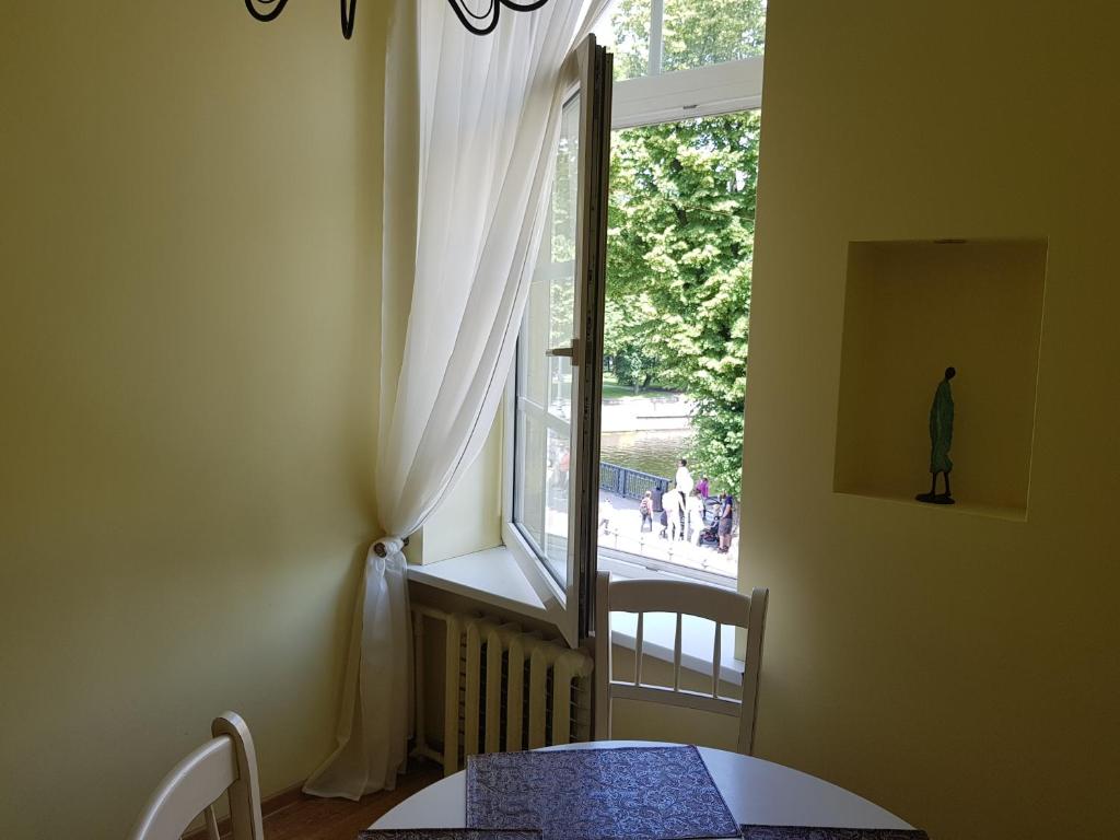 Cette chambre dispose d'une fenêtre avec une table, une table et des chaises. dans l'établissement Vilhelm's Apartment, à Klaipėda