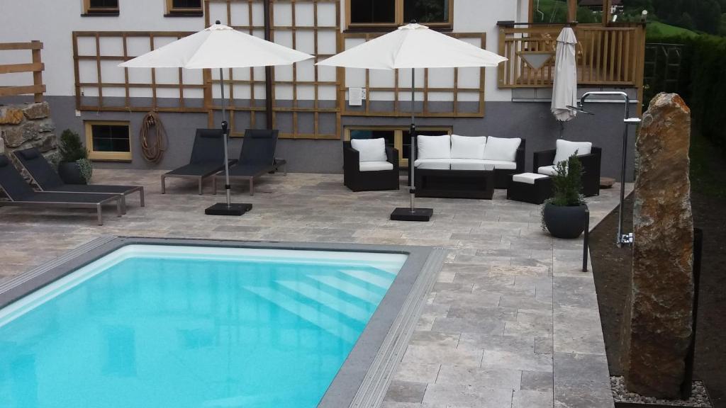 a swimming pool in a patio with chairs and umbrellas at Ferienhaus Marlen in Virgen
