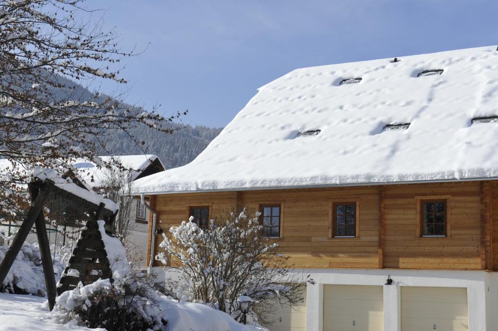 Cabaña de madera con nieve en el techo en Stranachwirt Apartments en Sankt Michael im Lungau