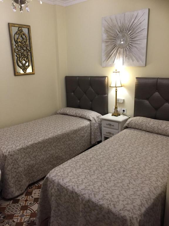 una habitación de hotel con 2 camas y una lámpara en Hostal Lojo, en Conil de la Frontera