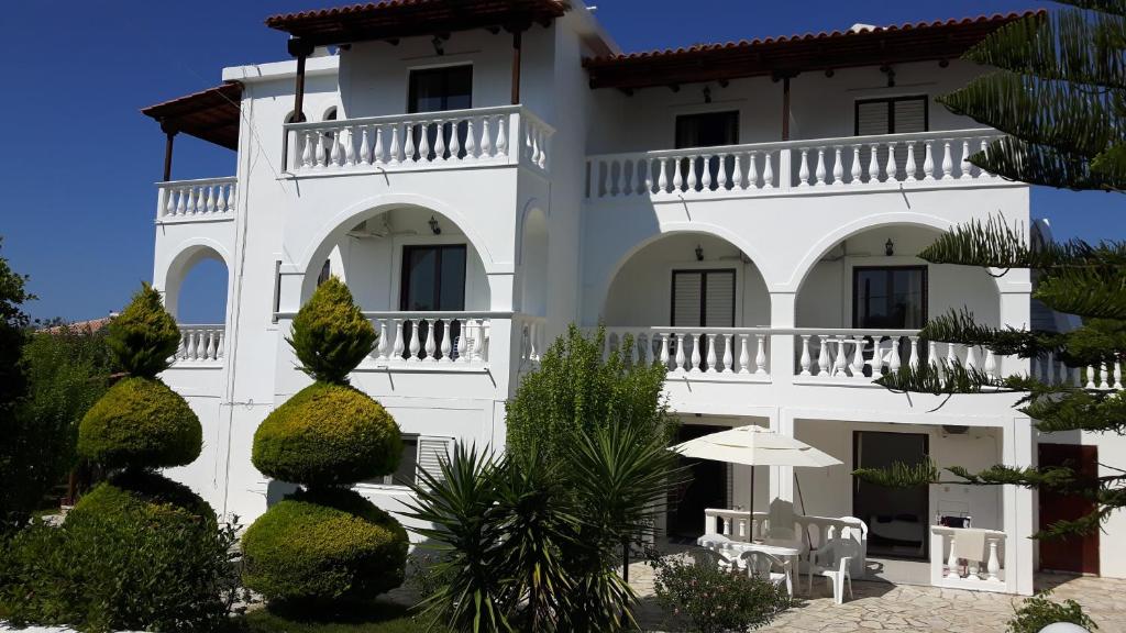 a white building with an umbrella in front of it at Rodis Studios in Tsilivi