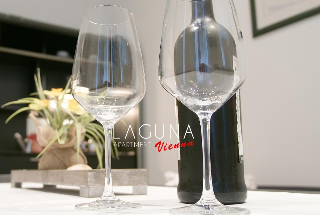 ウィーンにあるLaguna Apartmentのワイングラス2杯(ボトルの横のテーブルに座る)