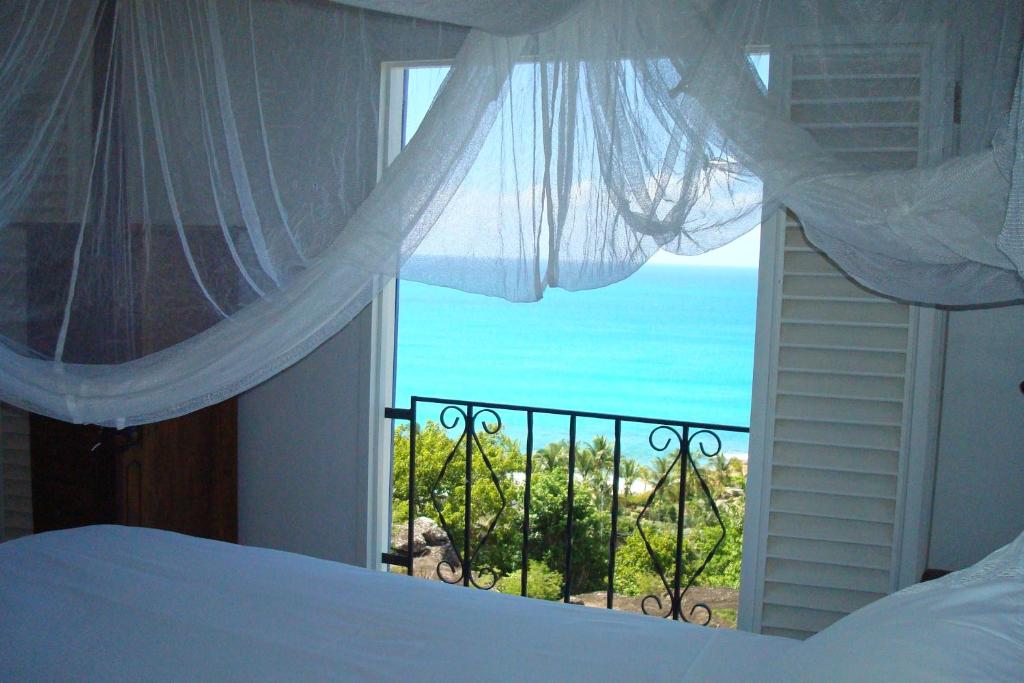 a bedroom with a window with a view of the ocean at Aloe Villa in Five Islands Village