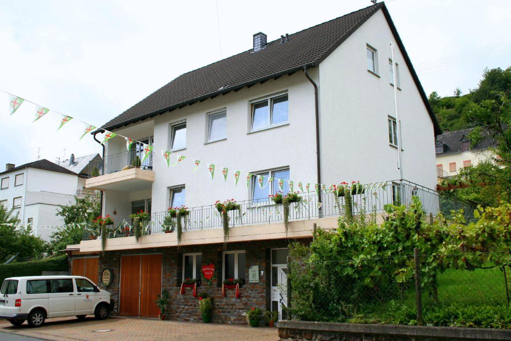 ein weißes Haus mit einem Balkon und einem Auto in der Unterkunft Ferienweingut Hensler in Briedel