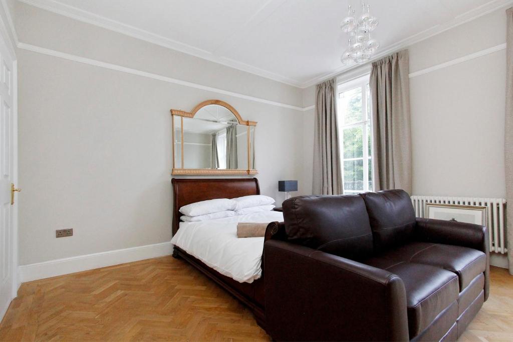 a bedroom with a bed and a chair and a mirror at Apartments At Marylebone in London