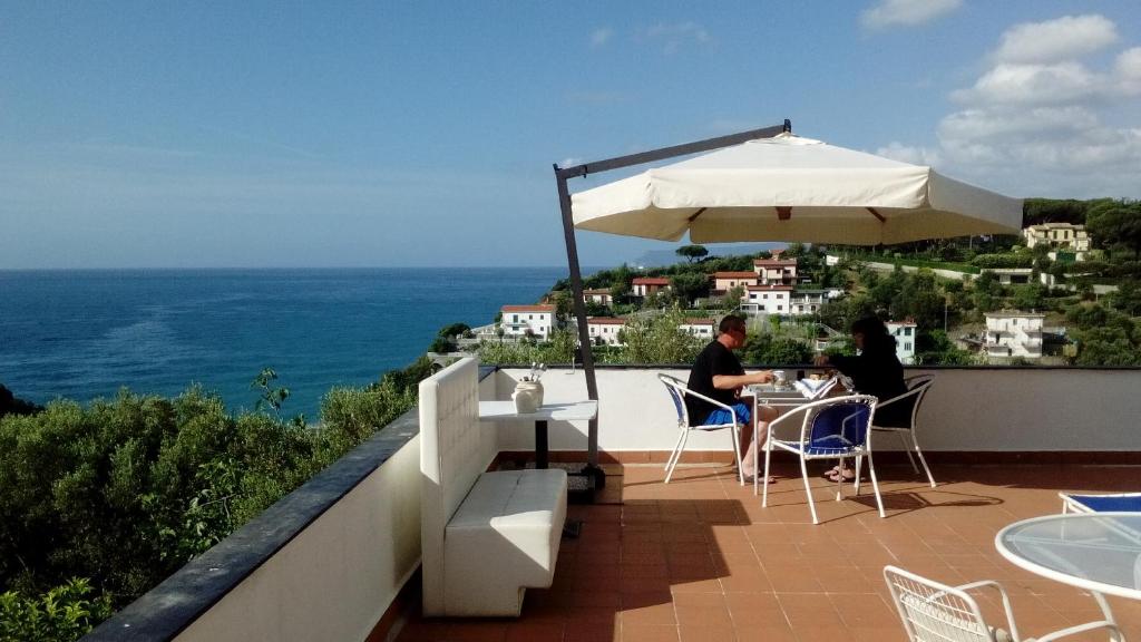 zwei Personen sitzen an einem Tisch auf einem Balkon mit Sonnenschirm in der Unterkunft Il Capriolo in Celle Ligure