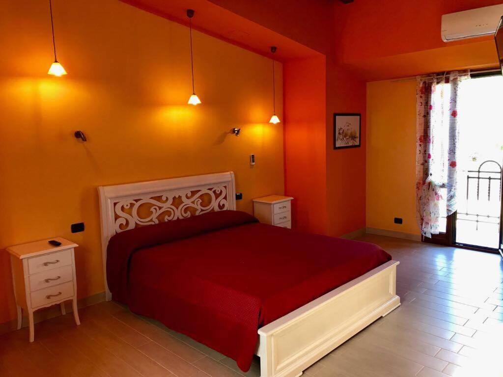 Eleven Bed & Breakfast في ريجّو دي كالابريا: غرفة نوم بسرير احمر وجدران برتقالية