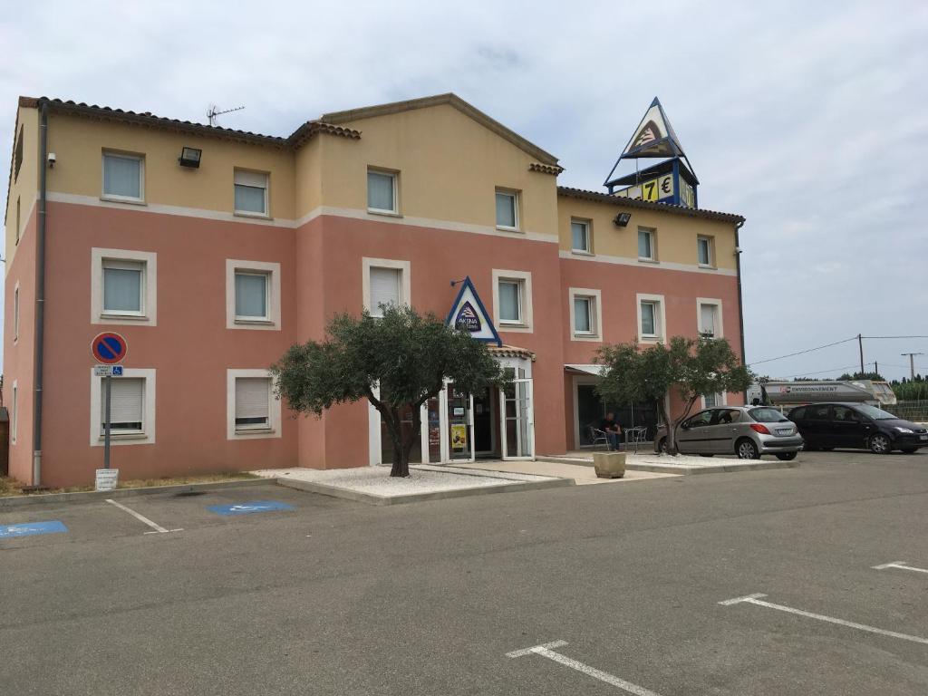un bâtiment avec une tour d'horloge dans un parking dans l'établissement Akena City Chateaurenard, à Châteaurenard