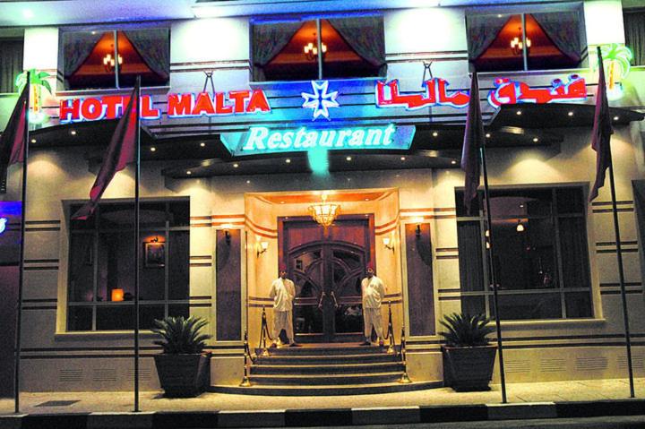 two men standing in front of a hotel at night at Hotel Malta in Meknès