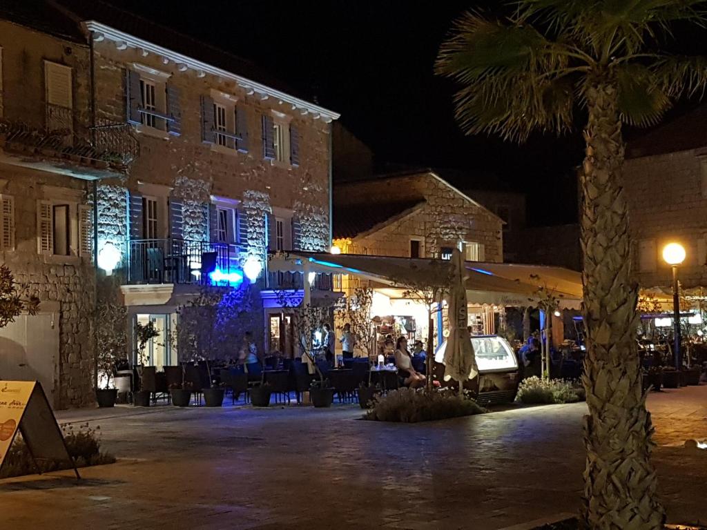 a building with tables and a palm tree at night at Villa Riva in Jelsa
