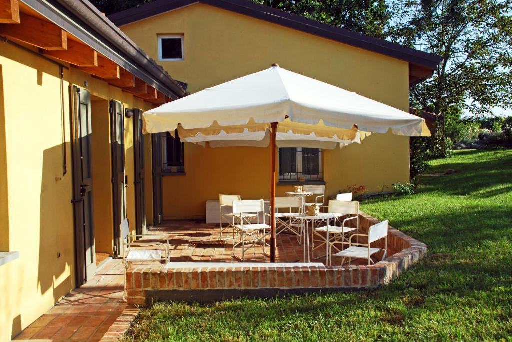 een patio met een tafel en stoelen onder een parasol bij Casale13 in Faenza