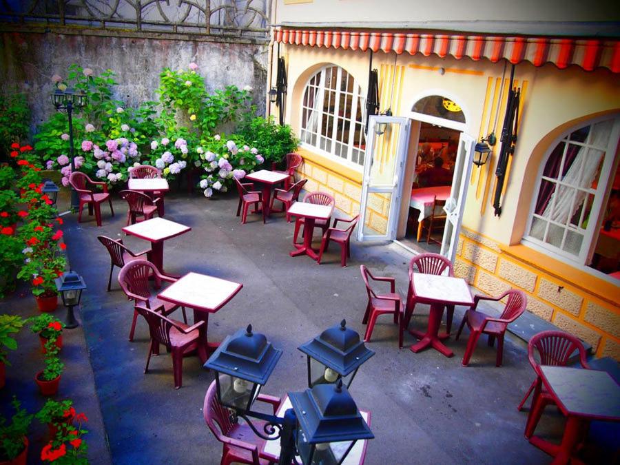 un groupe de tables et de chaises devant un bâtiment dans l'établissement Hotel Calvaire, à Lourdes