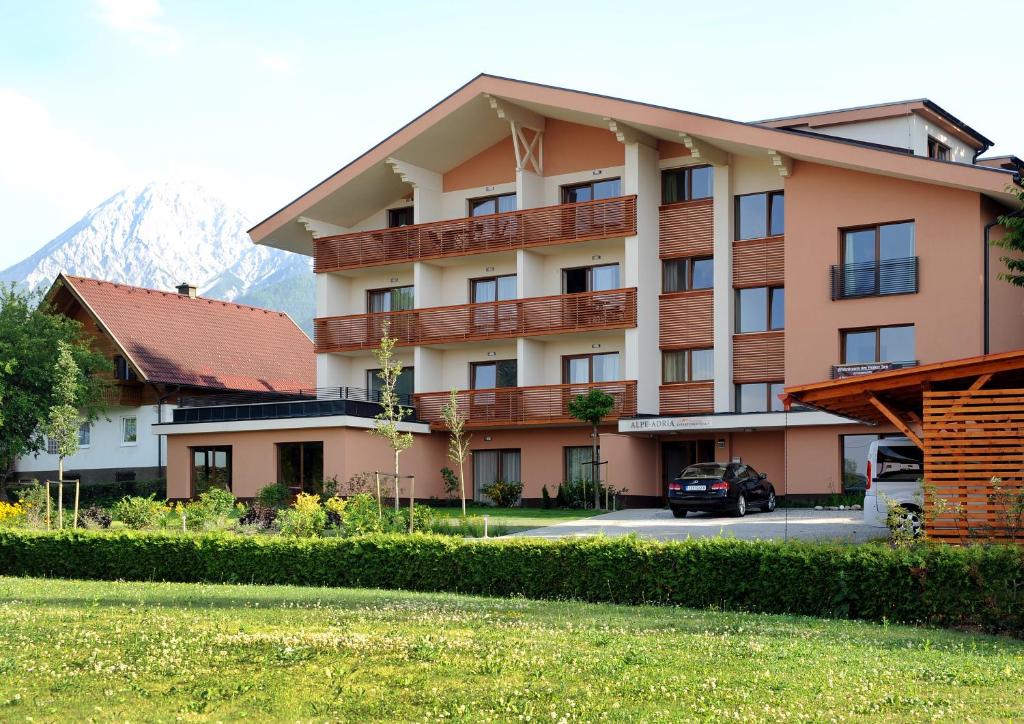 un gran edificio de apartamentos con montañas en el fondo en Alpe-Adria Apartments, en Oberaichwald