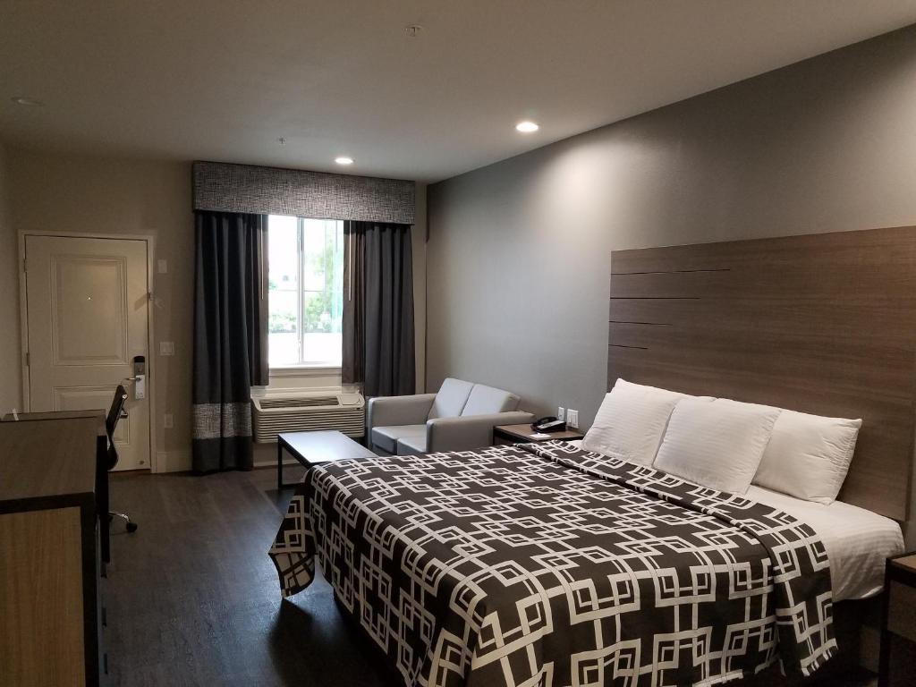 ein Hotelzimmer mit einem Bett und einem Stuhl in der Unterkunft Palace Inn Blue Tomball Parkway in Houston