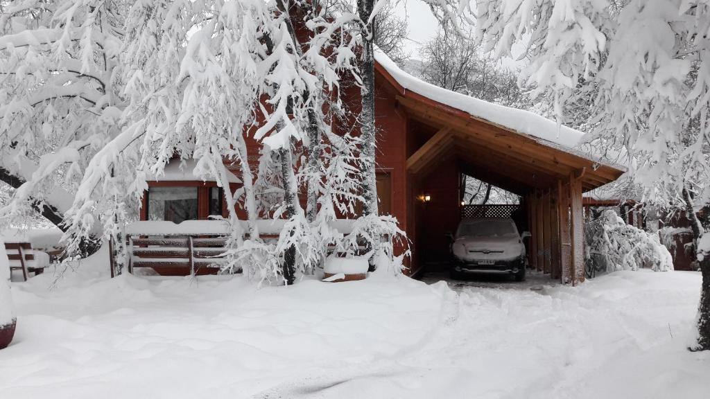 eine schneebedeckte Hütte mit einem davor geparkt in der Unterkunft Cabañas Tronco Mayen in Las Trancas