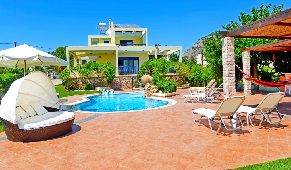 a patio with a pool and chairs and a house at Villa Angelina in Pefki