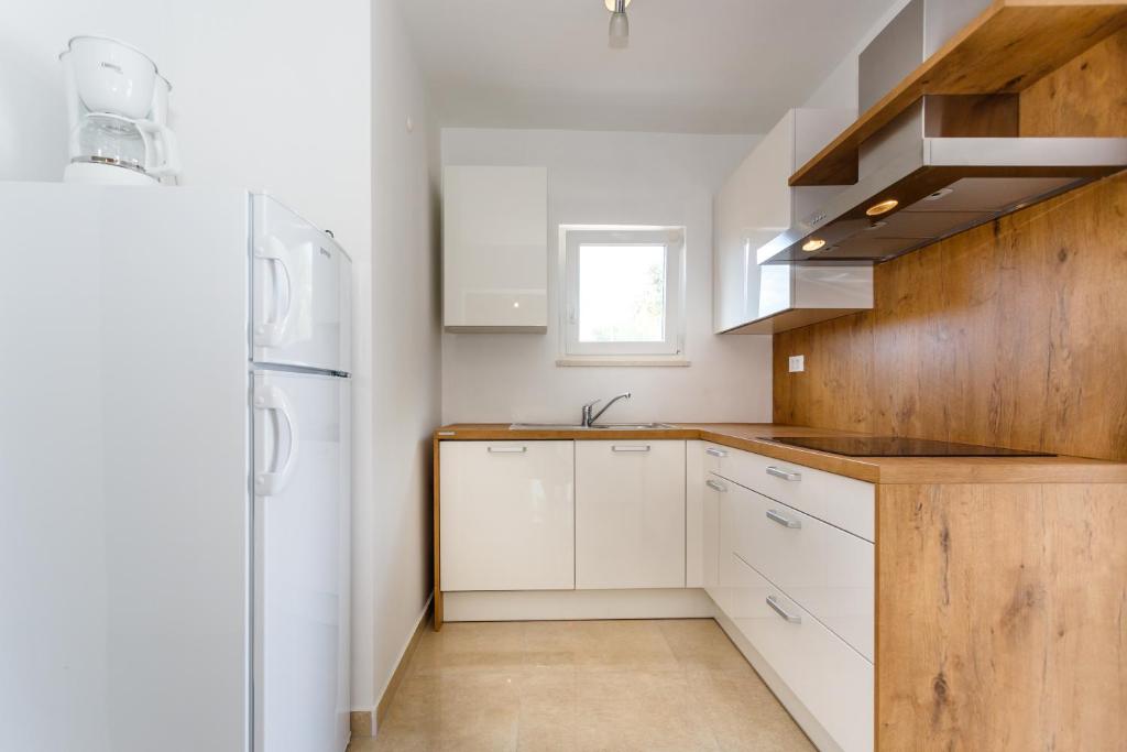 una cucina con armadietti bianchi e frigorifero bianco di Apartman Maslina a Krk