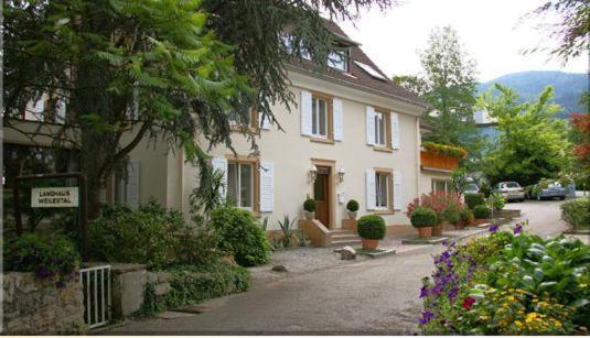 ein großes weißes Haus mit Blumen davor in der Unterkunft Landhaus Weilertal in Badenweiler