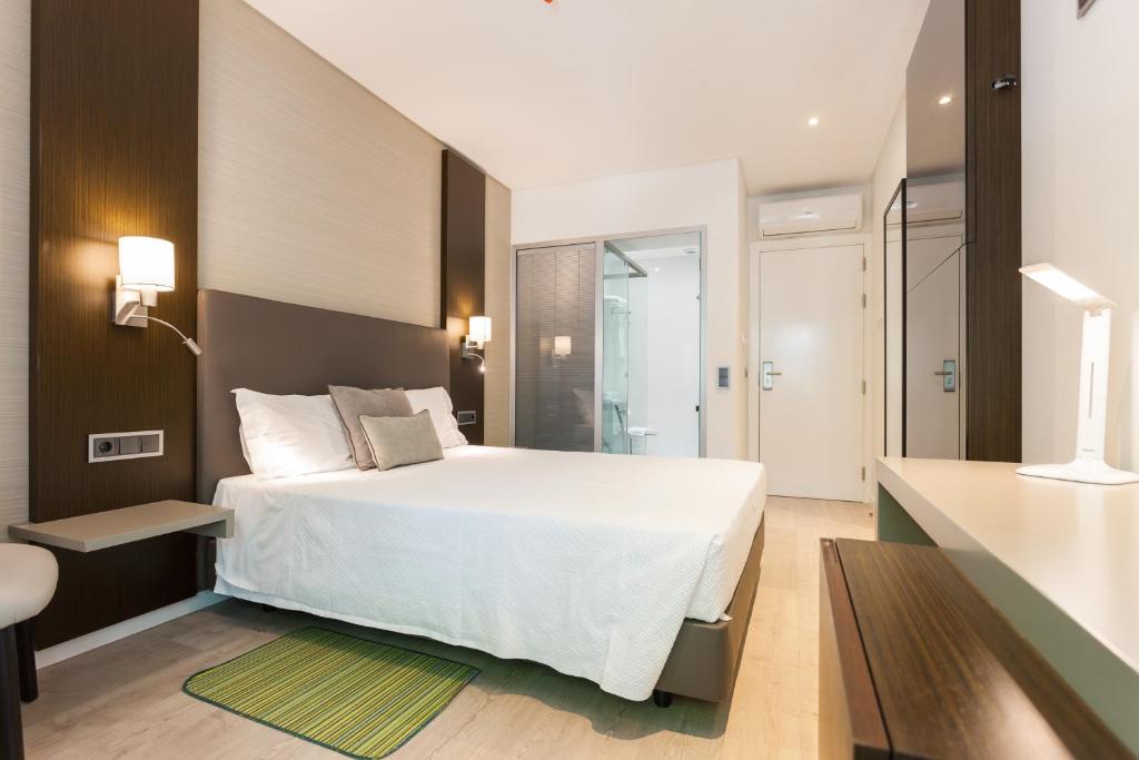 a bedroom with a white bed and a bathroom at Hotel Capital Lisboa in Lisbon
