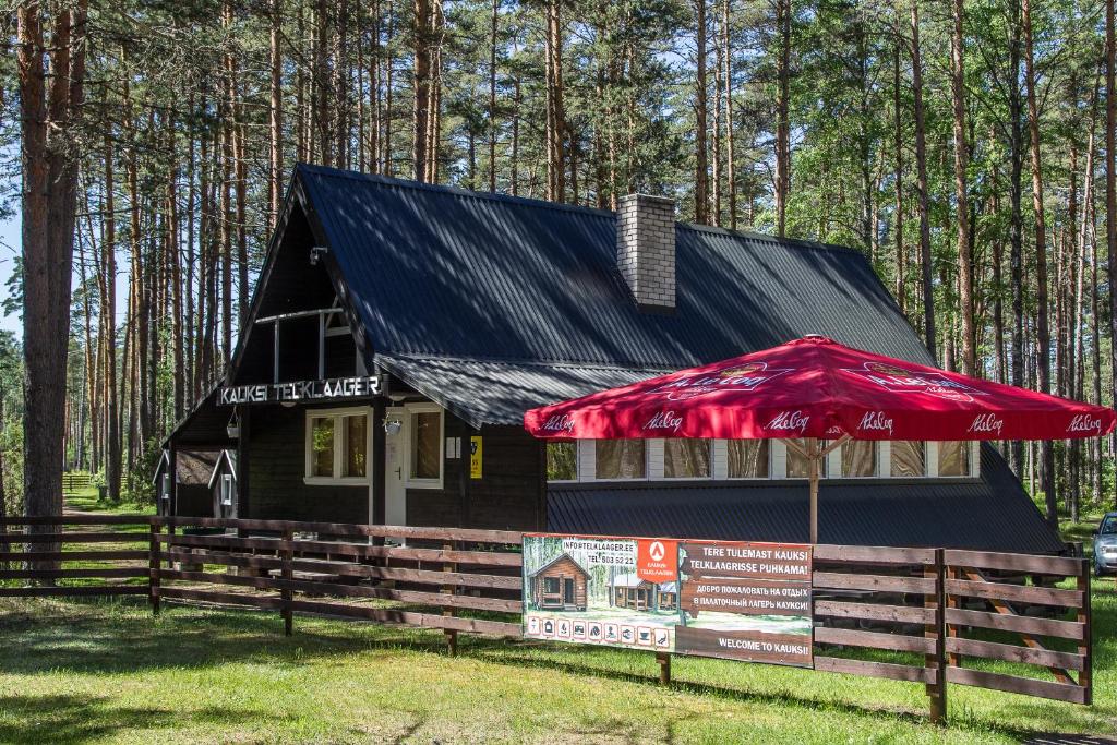 ein Haus mit einem roten Regenschirm davor in der Unterkunft Kauksi Campsite in Kauksi