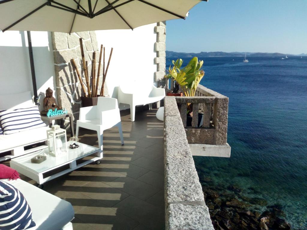 a patio with chairs and an umbrella and the water at Principe in Sanxenxo