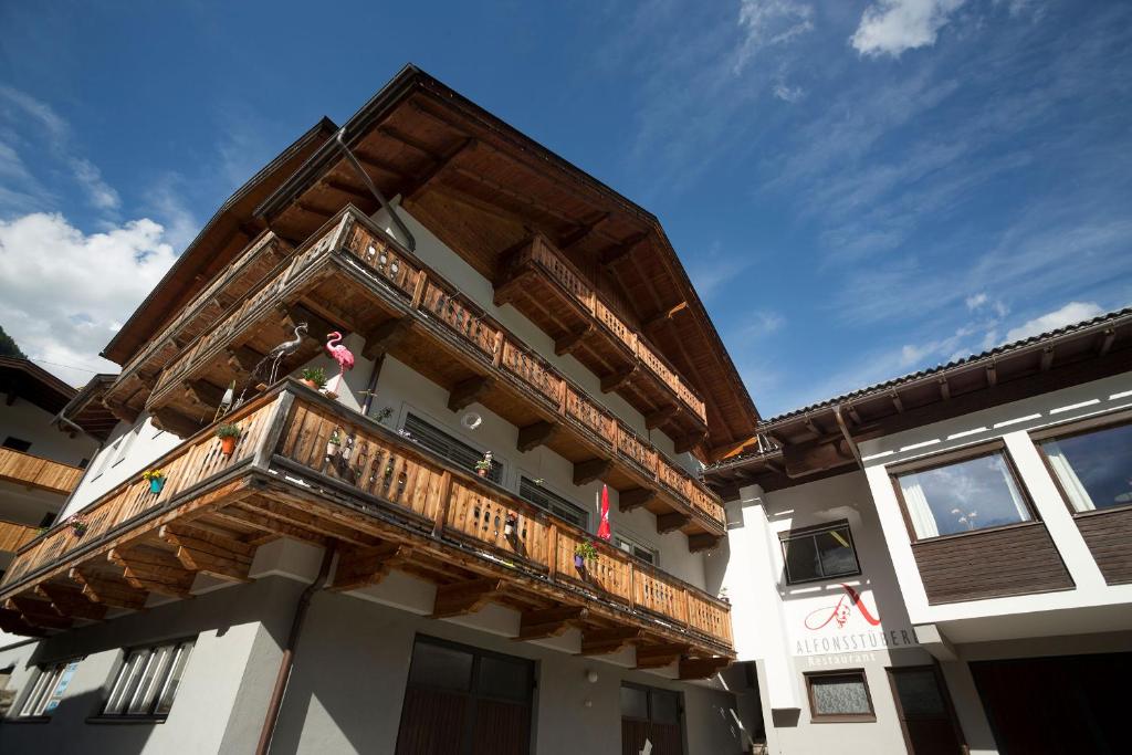 un balcón de madera en el lateral de un edificio en Alfonsstüberl - Ferienwohnungen & Restaurant, en Innervillgraten