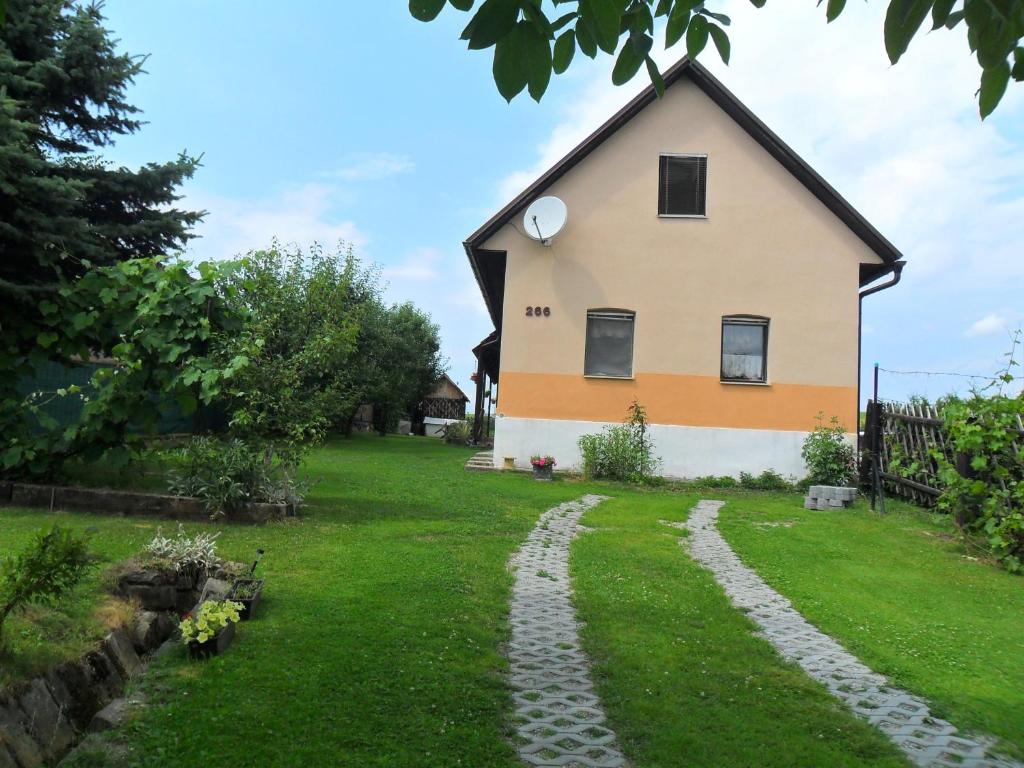 a house with a stone path in front of a yard at Útulná chalupa za potokom Sklené in Sklené