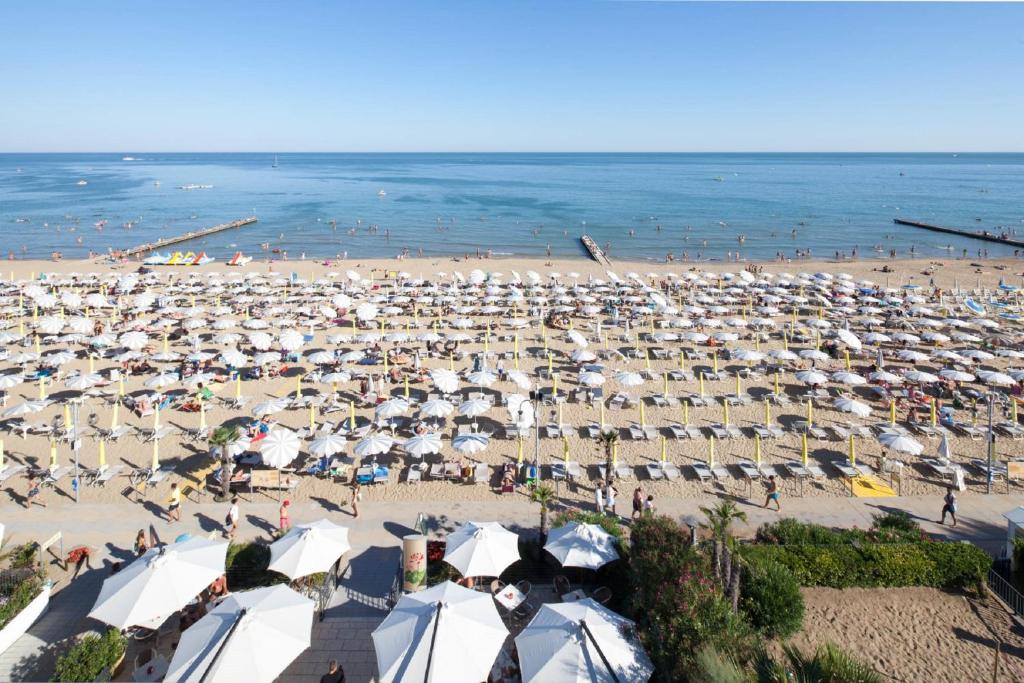 a beach with a lot of umbrellas and the ocean at Hotel Columbia & Ninfea in Lido di Jesolo