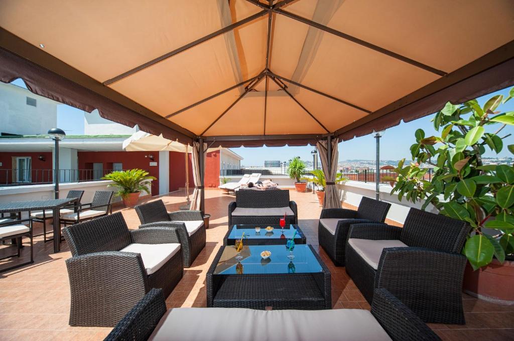 un patio esterno con sedie, tavoli e un grande ombrellone di Hotel Tiempo a Napoli