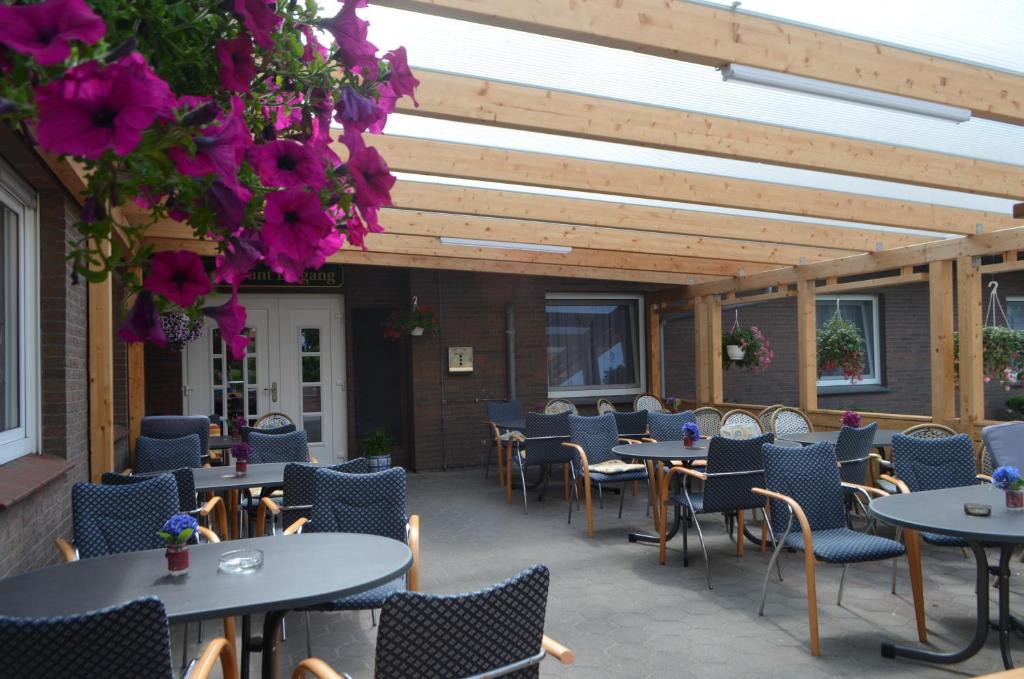 een patio met tafels, stoelen en bloemen bij Am Alten Hafen in Neuharlingersiel