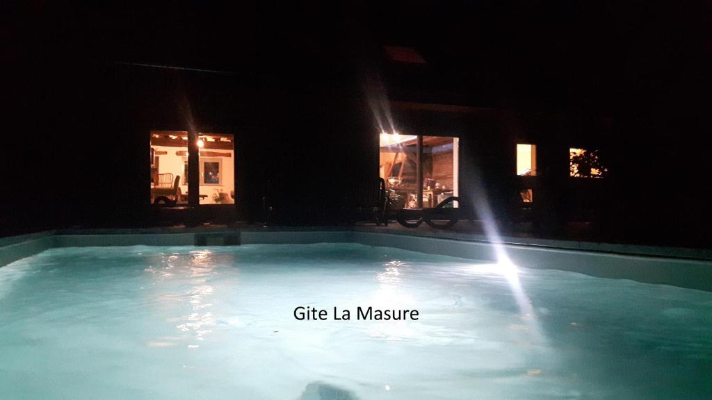a swimming pool at night with the lights on at La Masure in Érezée