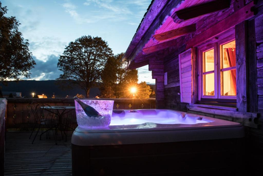a jacuzzi tub outside of a house with purple lighting at Hôtel Le Manoir des Montagnes in Les Rousses