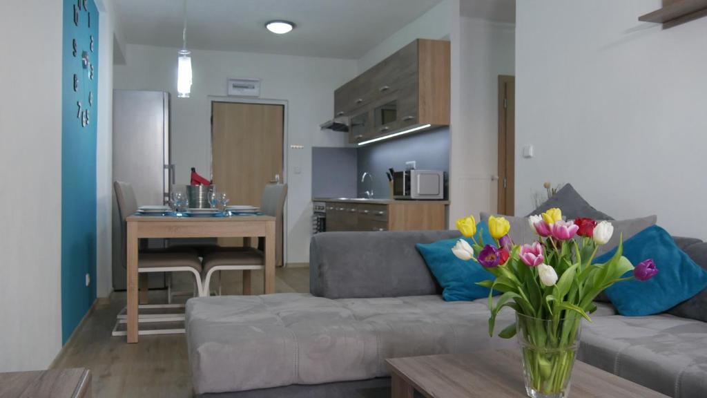 ein Wohnzimmer mit einem Sofa und einem Tisch mit Blumen in der Unterkunft Všemina Apartman in Lužkovice