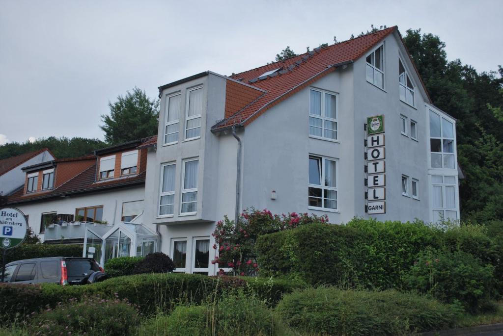 Hotel Garni Am Schäfersberg في نيدرنهاوسن: مبنى ابيض عليه لافته جانبيه