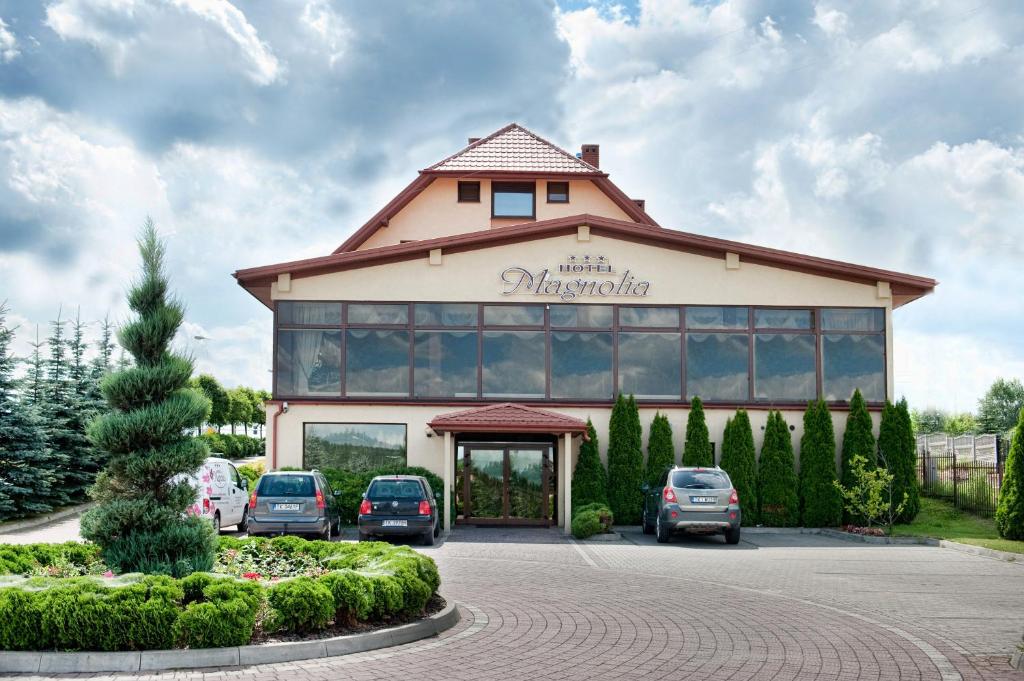 duży budynek z samochodami zaparkowanymi na parkingu w obiekcie Hotel Magnolia w Kielcach