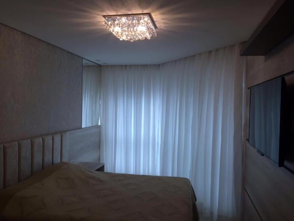Schlafzimmer mit einem Bett und einem Fenster mit einem Kronleuchter in der Unterkunft Residencial Celebretty 602 Capao da Canoa locação de temporada in Capão da Canoa