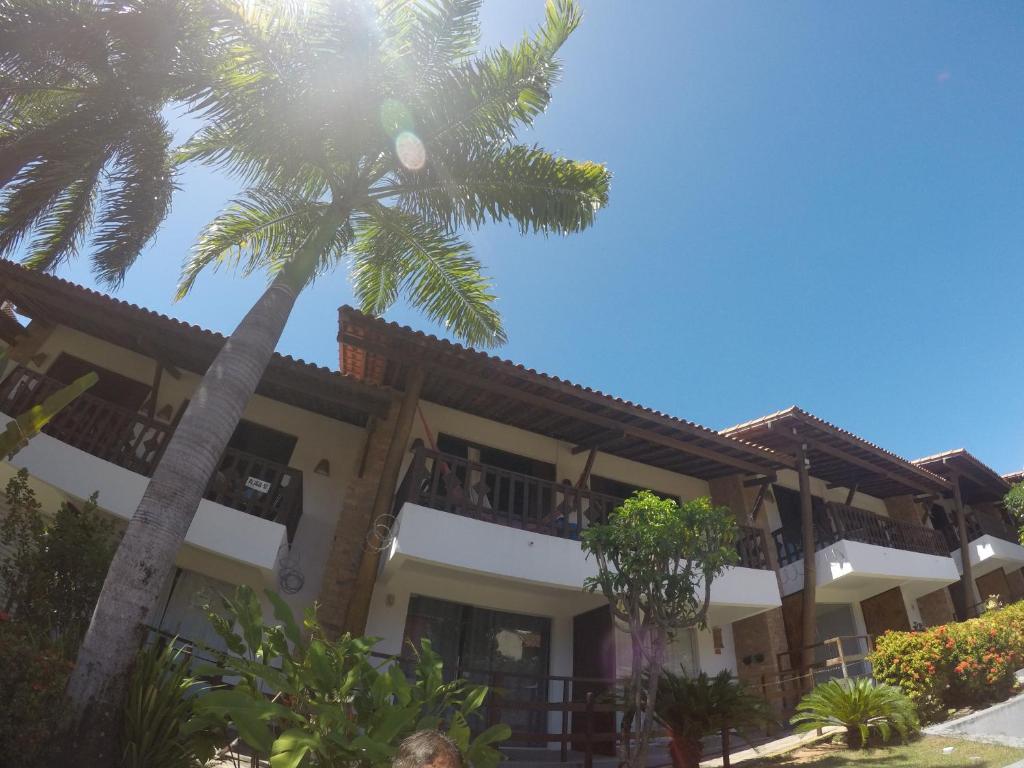 a building with a palm tree in front of it at Apartamentos La Piazzetta Duplex in Pipa