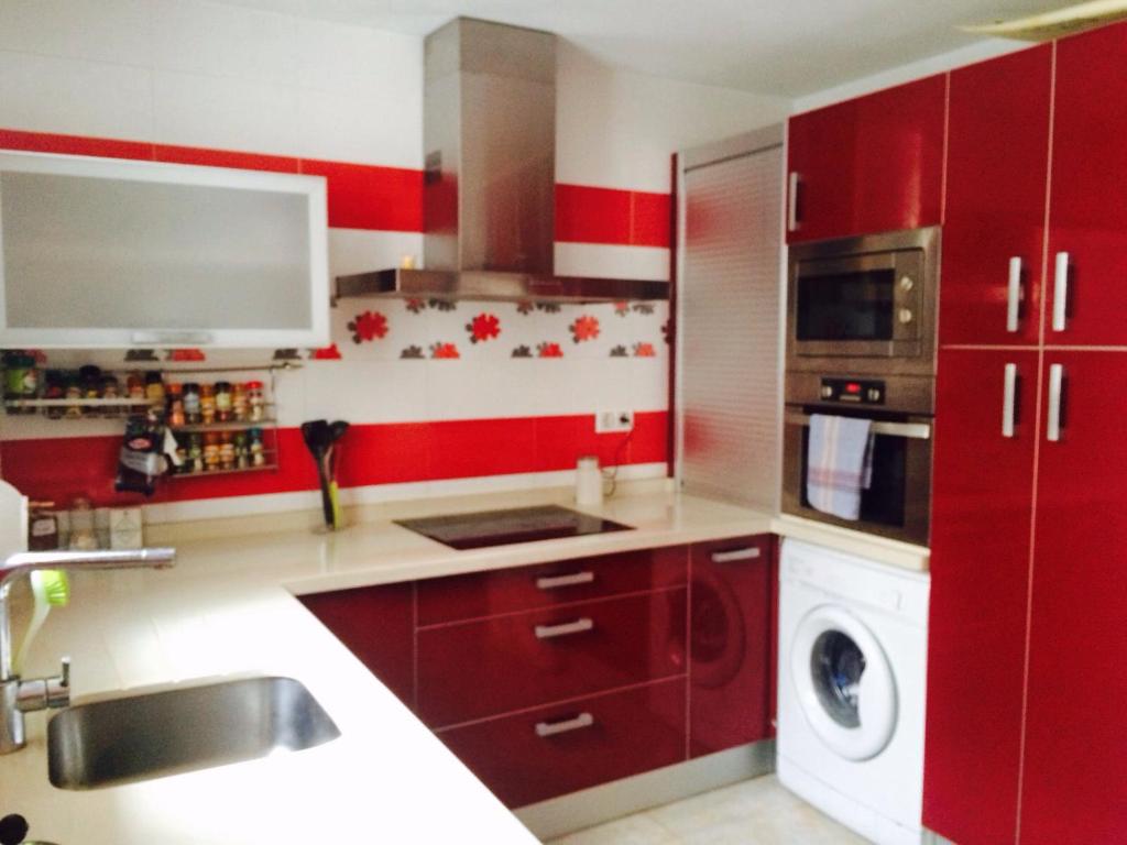 カディスにあるLa casita de Claudiaのキッチン(赤いキャビネット、洗濯機、乾燥機付)