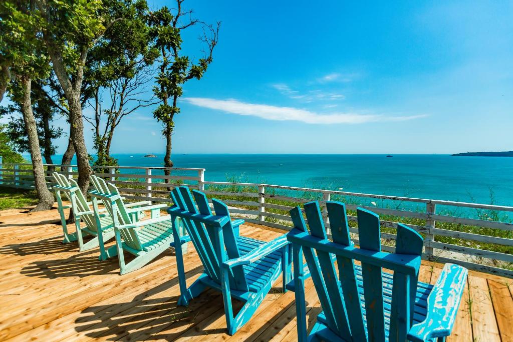 a row of blue chairs sitting on a deck overlooking the ocean at St Anastasia Hotel in Burgas City